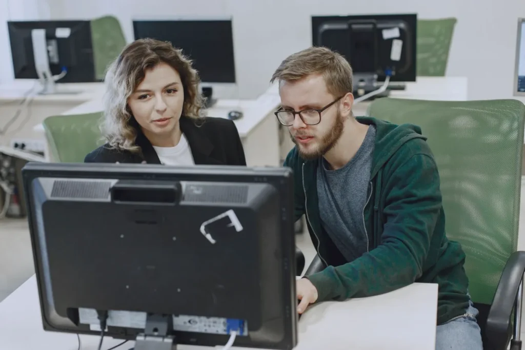 Dos personas revisando juntas un computador en una oficina