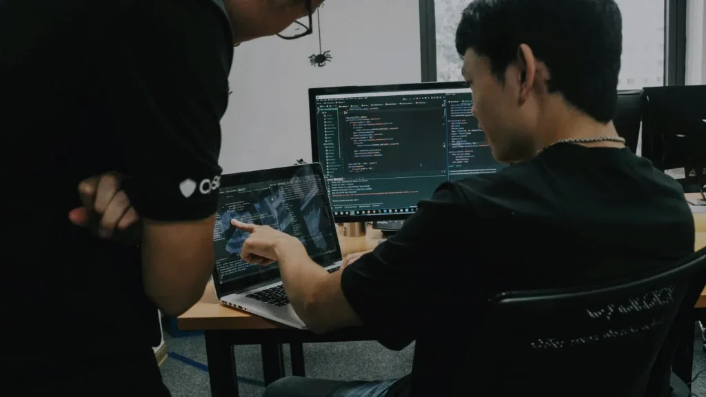Dos técnicos revisan código en un computador